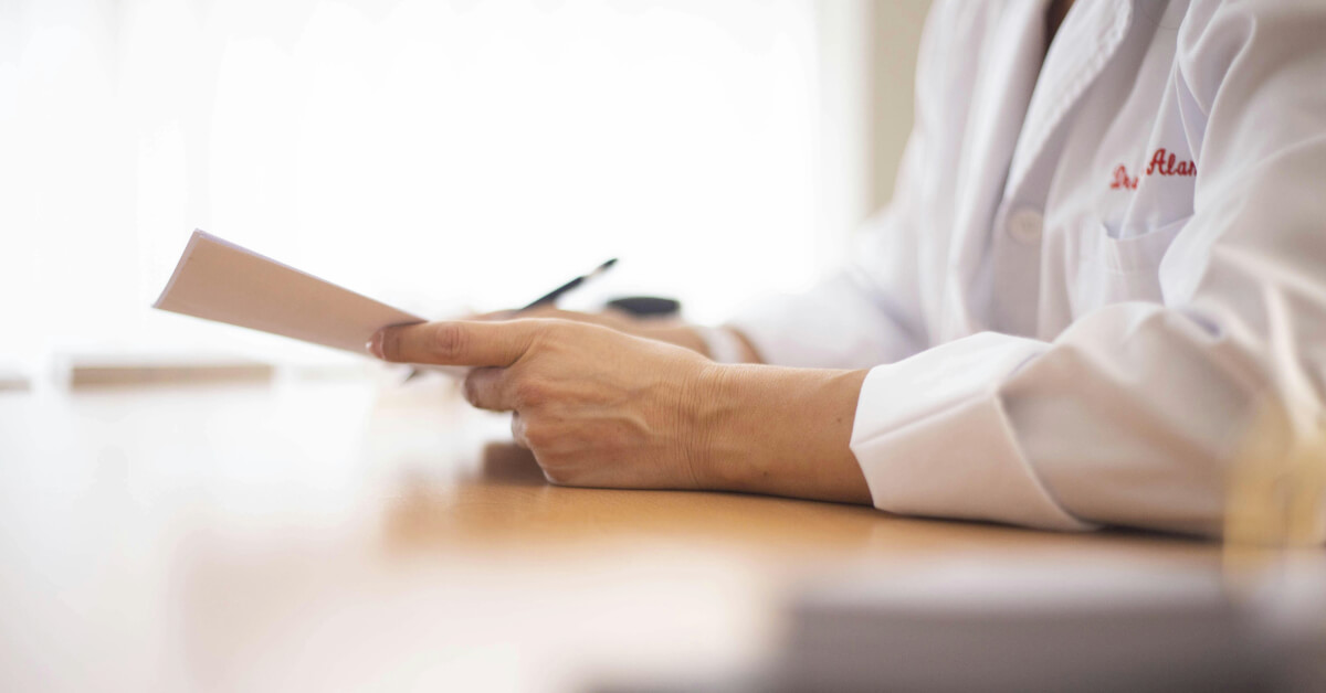 Doctor sitting at a desk holding a pen and paper