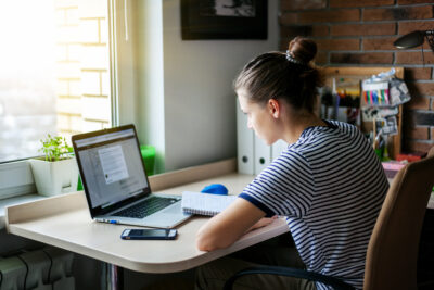 Girl student freelancer working with laptop at home by the window, education and remote work, programmer, online business