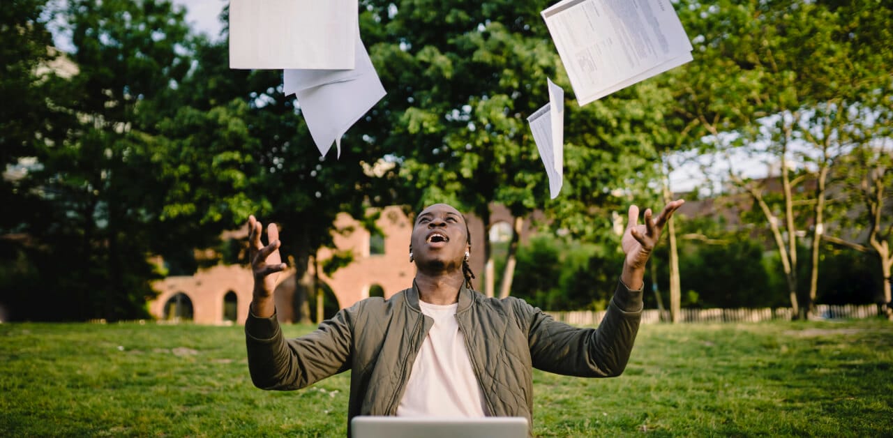 Man behind laptop throwing exam papers in the air - comlex score release