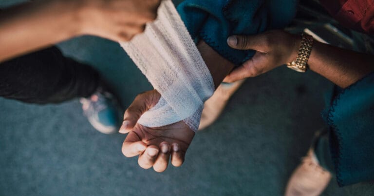 Someone wrapping another person's arm in gauze