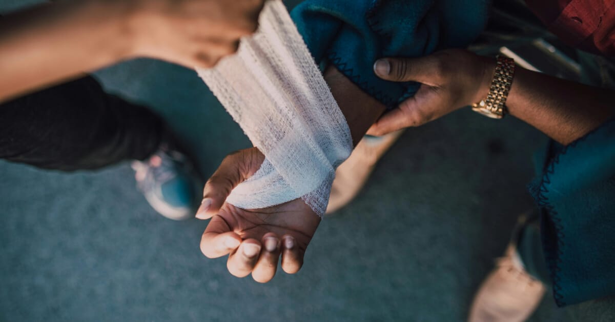Crisis support blog banner Someone wrapping another person's arm in gauze
