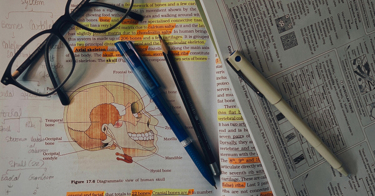 Desk filled with a book, pens and glasses