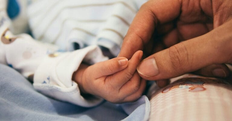 Nurses hand holding a babies hand