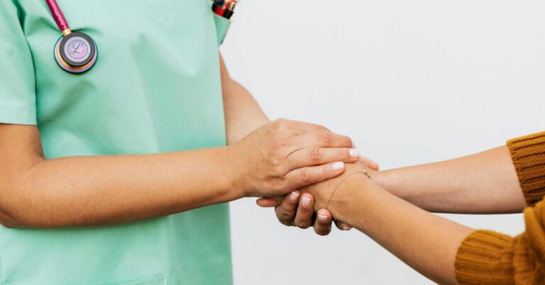Nurse holding a patients hands