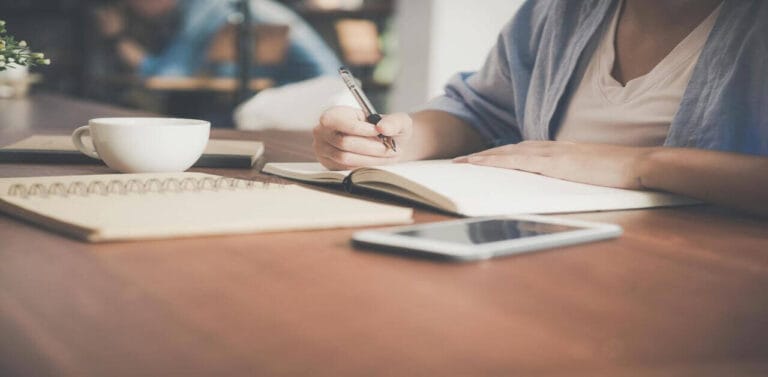 A studying nurse writing notes in their book