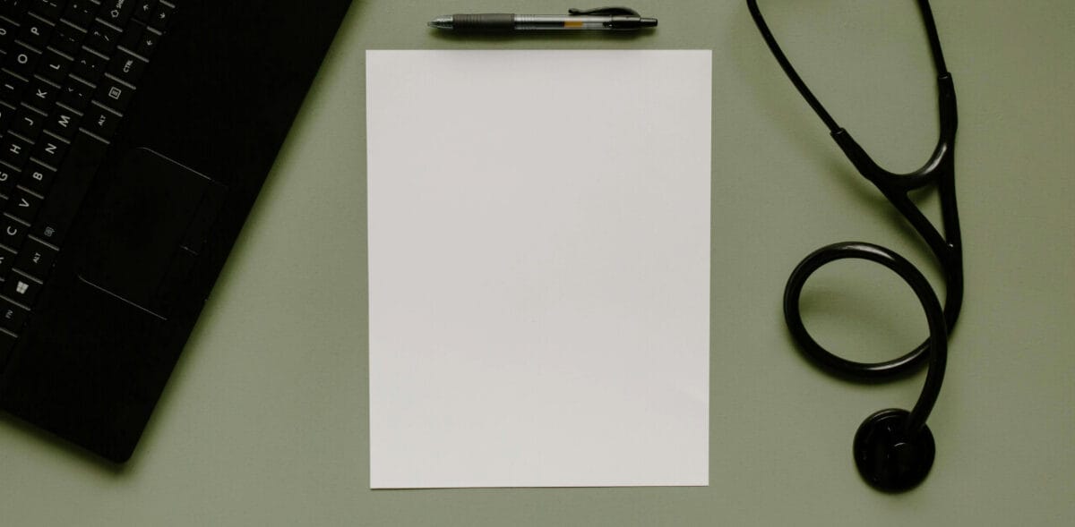 Blank piece of paper next to a laptop and a stethoscope - NCLEX vs. USMLE Blog