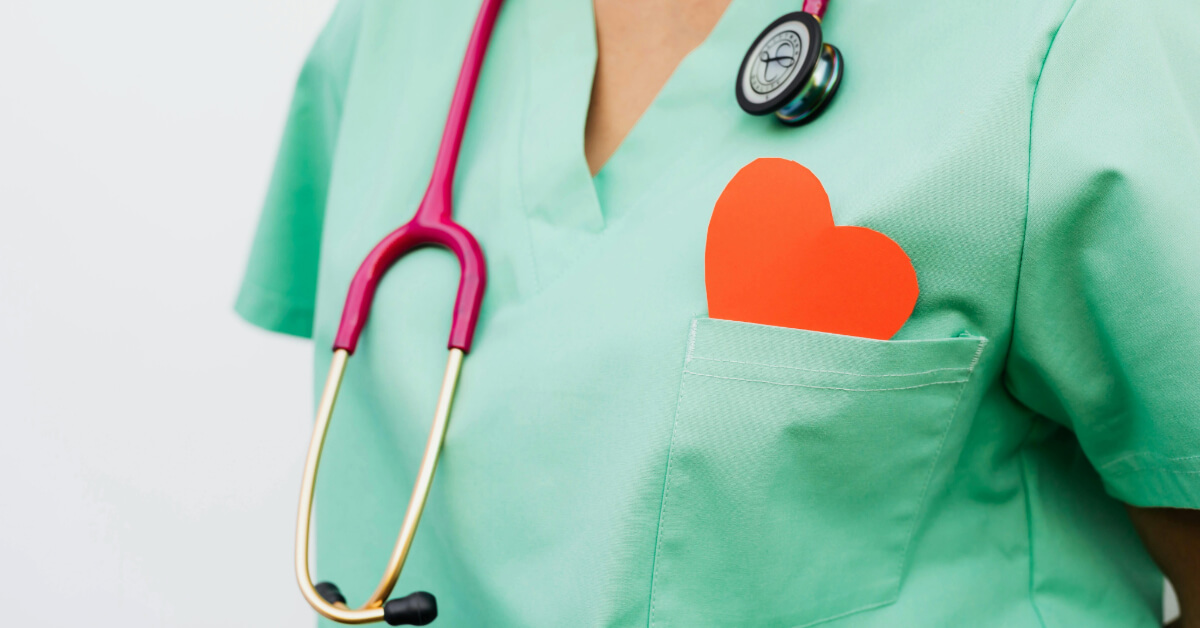 Nurse wearing scrubs, a stethoscope and a heart in her breast pocket