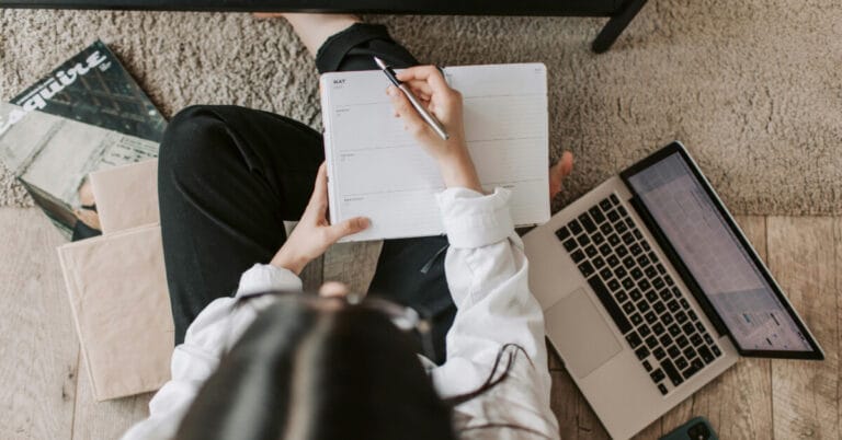 Person with a laptop writing in their agenda