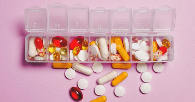 A pill box overflowing with multiple types of pills
