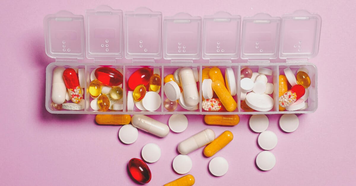 A pill box overflowing with multiple types of pills